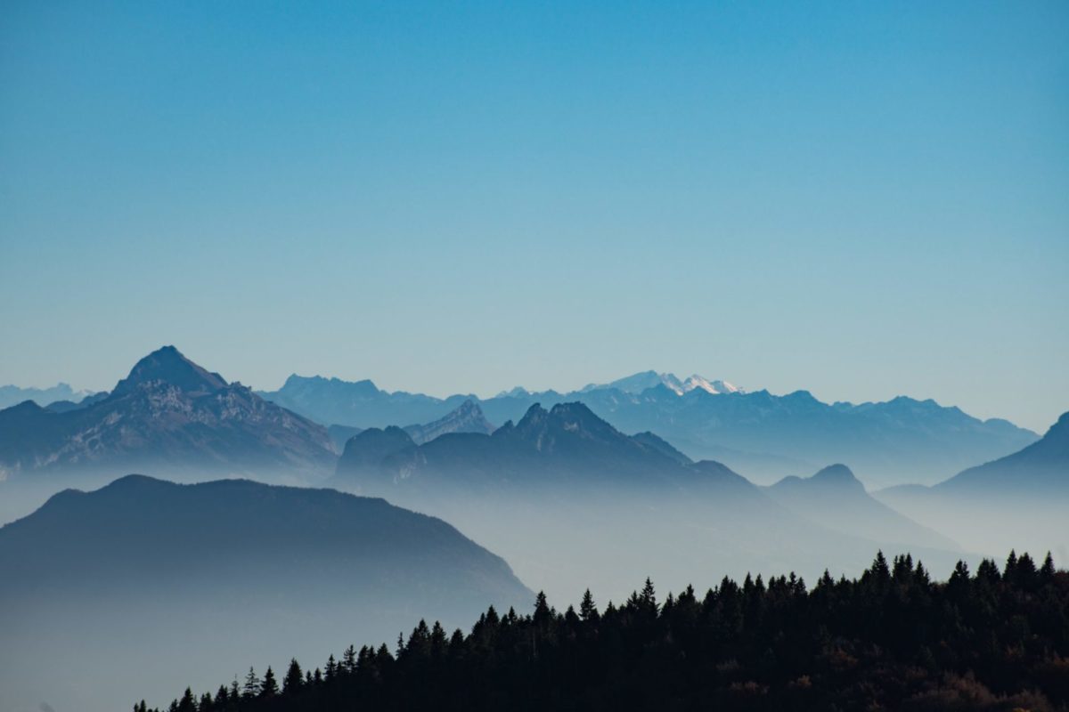 Foggy mountain range near the forest under the blue sky