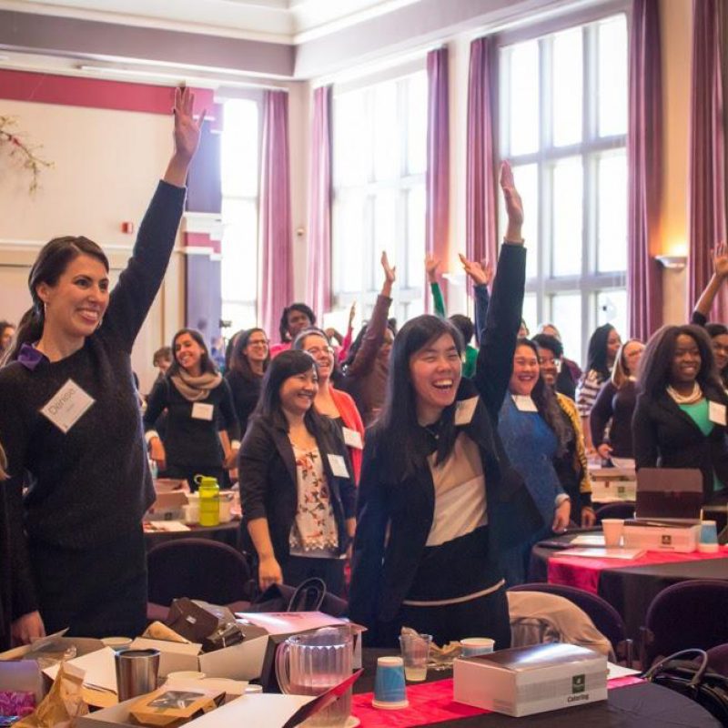 An audience standing up with hand raised